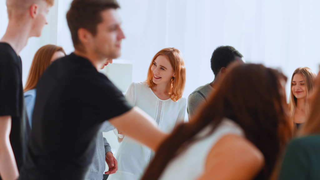 A group of young adults, mostly out of focus, with a smiling young woman with red hair in the background, illustrating a comparison between Level 2 vs Level 3 Youth Work qualifications.
