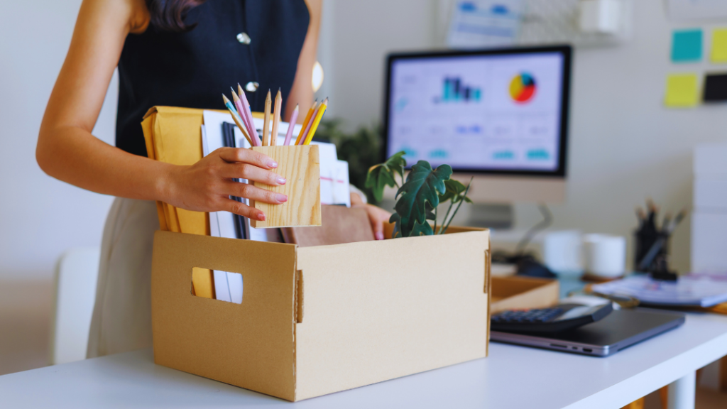 Professional woman packing desk items in cardboard box, symbolizing mid-life career transition and adult learning for job change.